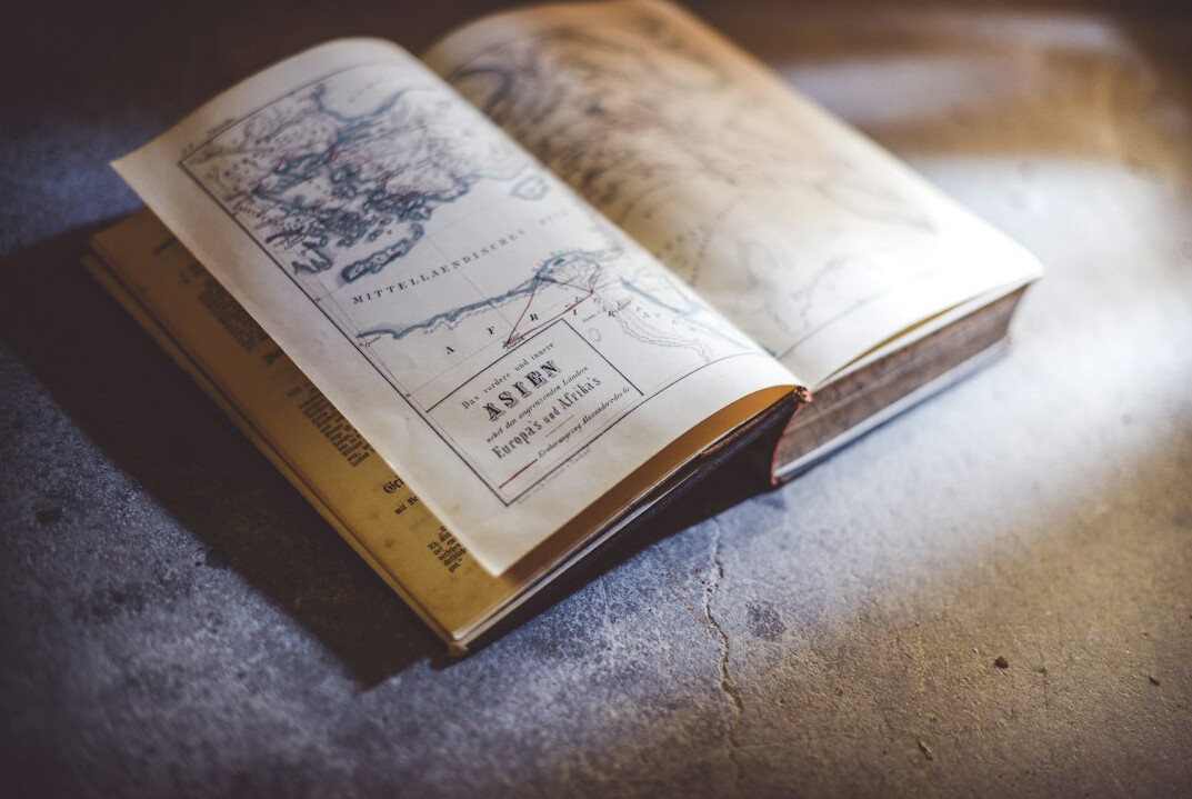 Open notebook with a vintage city map and a magnifying glass