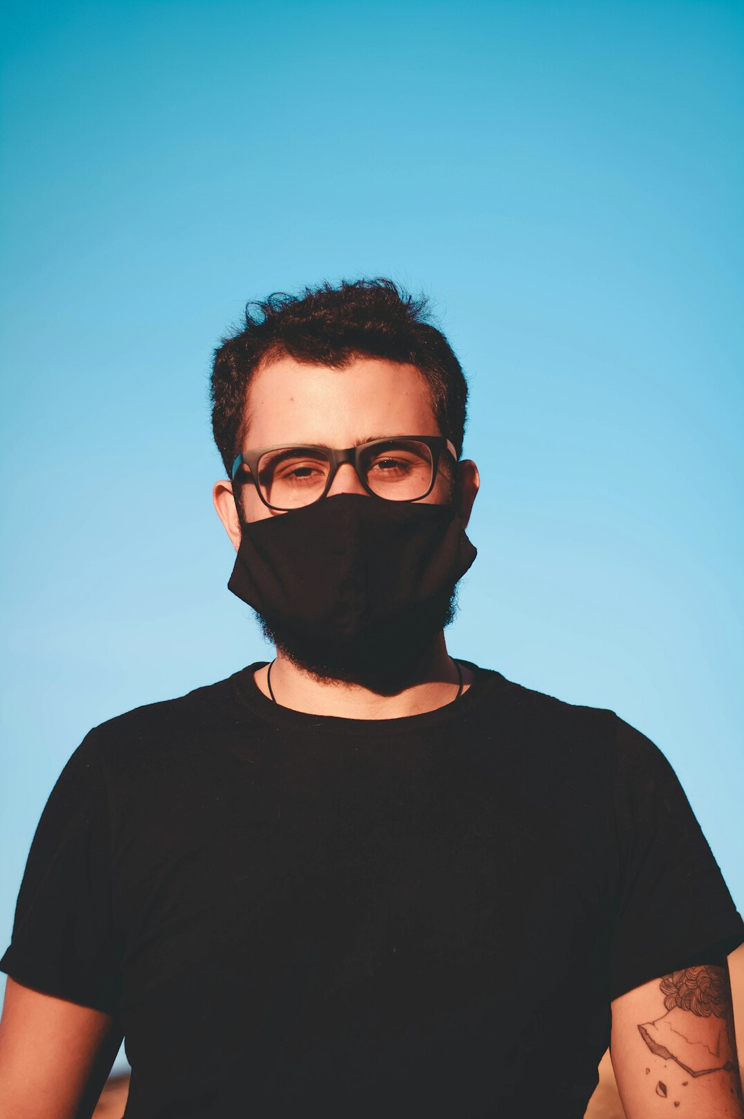 Studio portrait of a man with a beard and glasses on a blue background