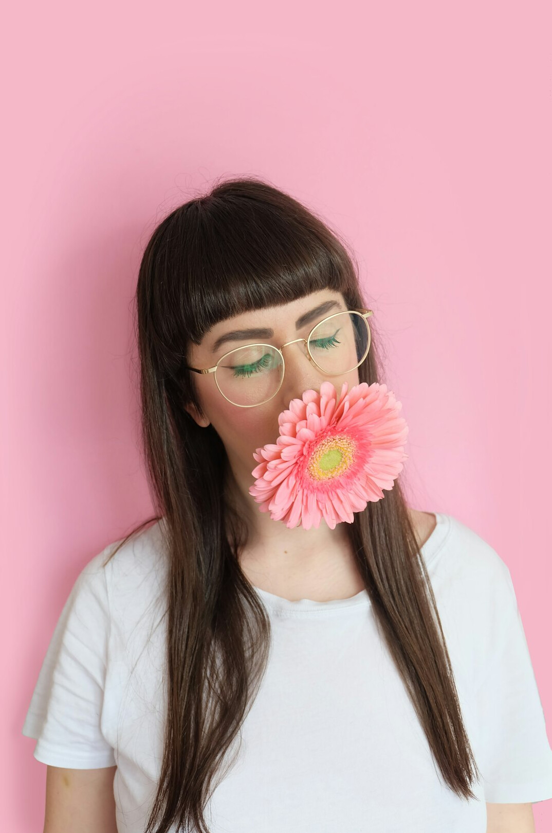 Studio portrait of a woman with glasses and a bob haircut on a pink background