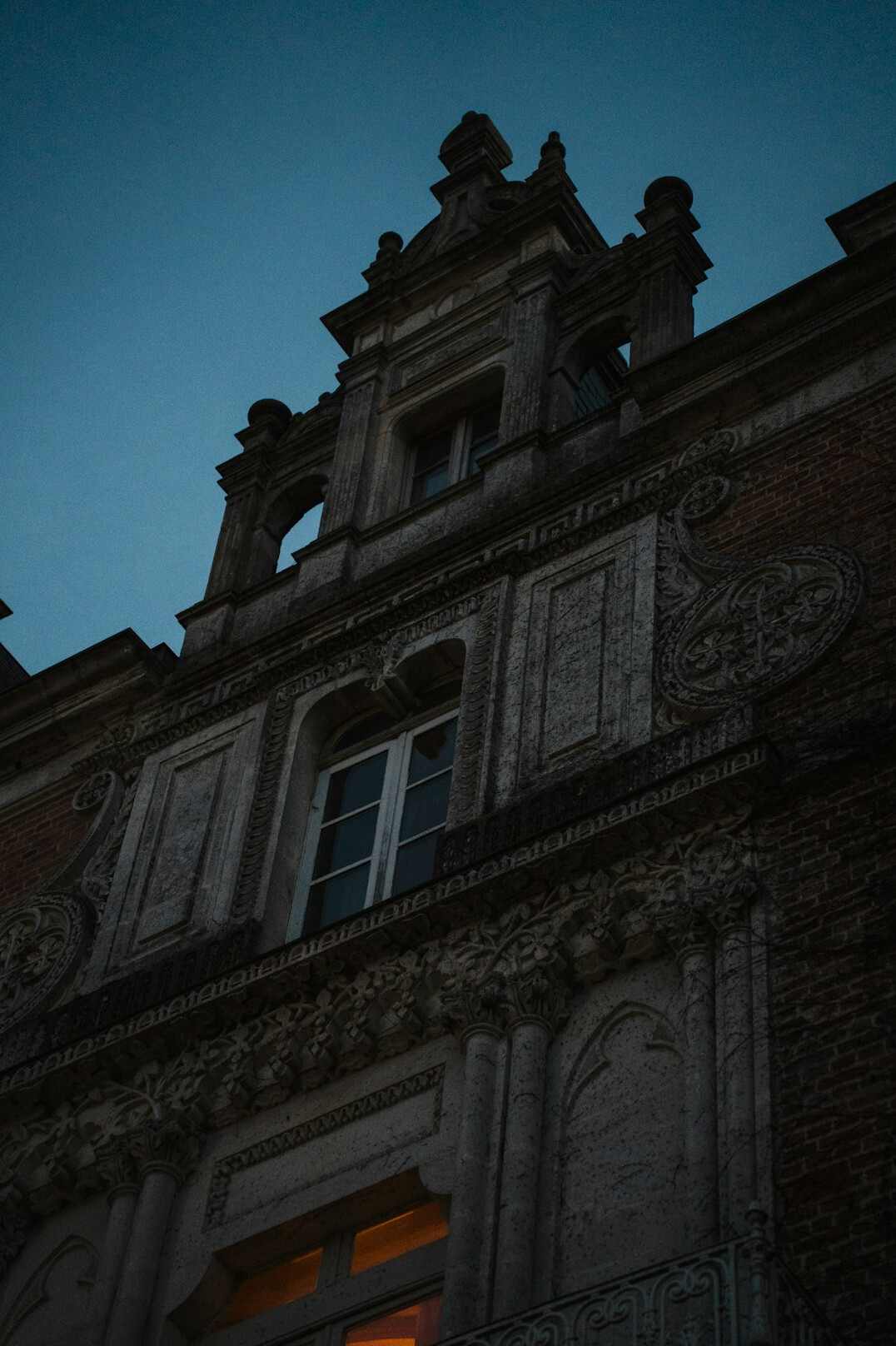 Old historic building facade at dusk with a single lit window