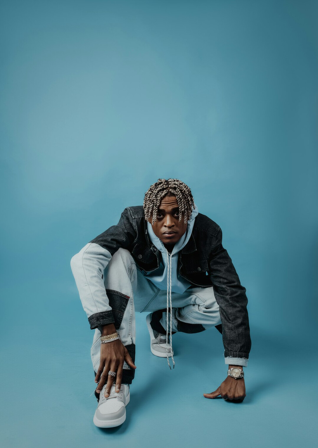 Studio portrait of a man in a hoodie on a light blue background